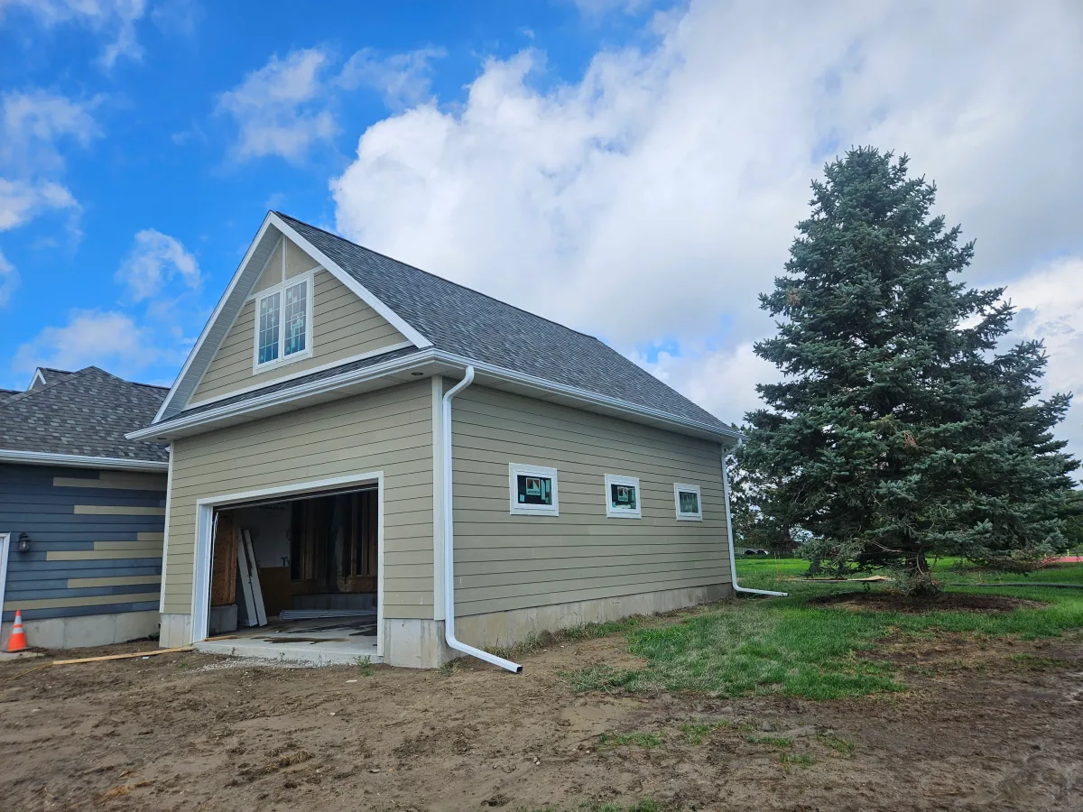 The same garage addition after installation, with white seamless gutter along the eave and a white downspout running down the corner