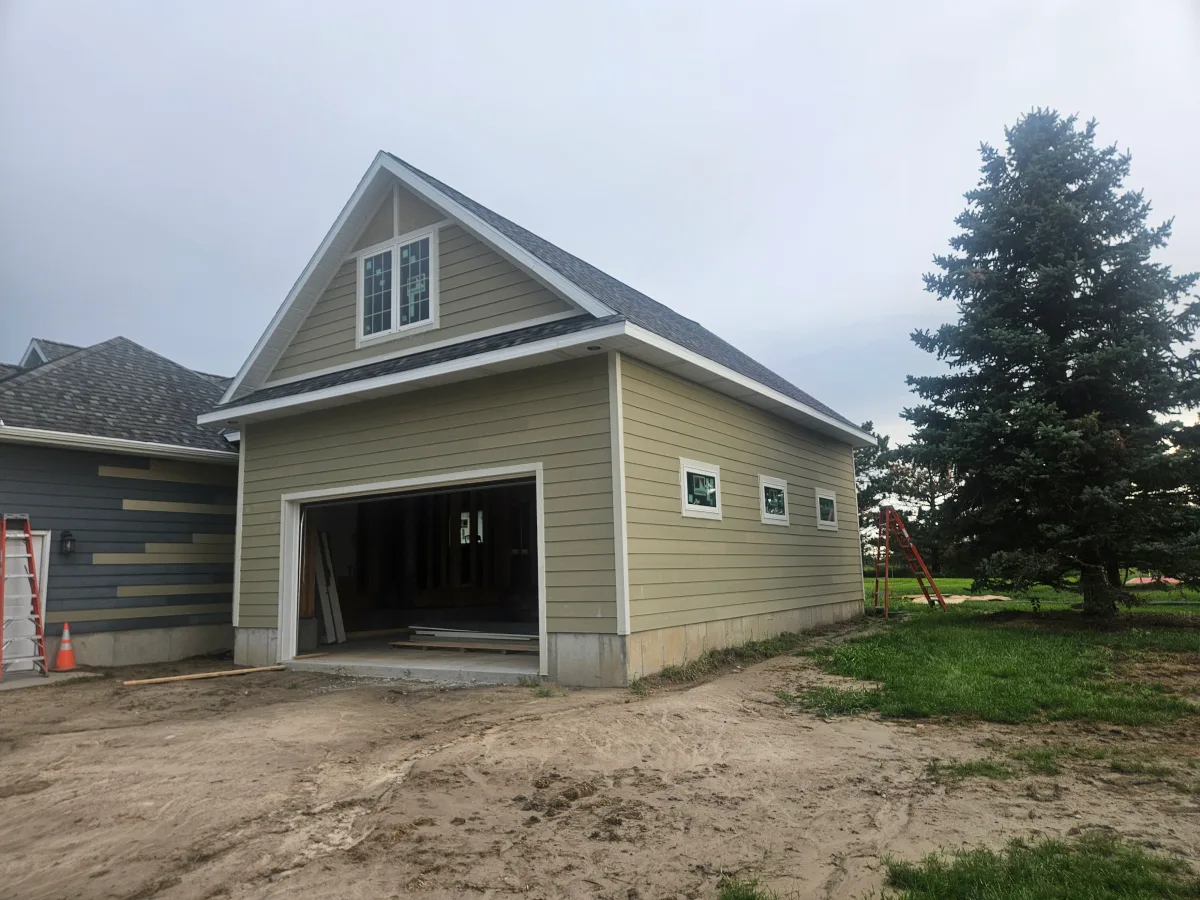 New detached garage addition with sage lap siding and bare roof edge, before gutters were installed
