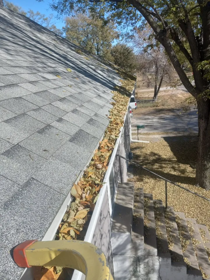 A gutter packed with wet leaves and debris before cleaning