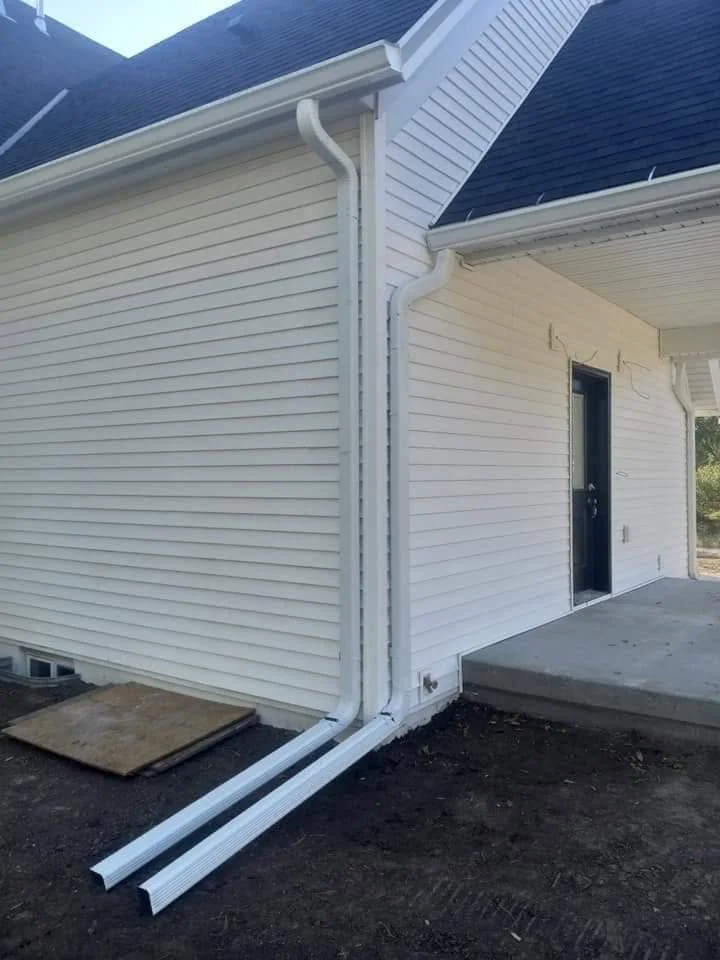 Newly installed white seamless gutters and downspout on a residential home